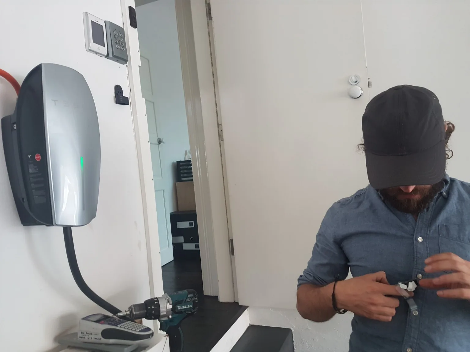 Electrician working beside a Tesla electric vehicle wall charging station